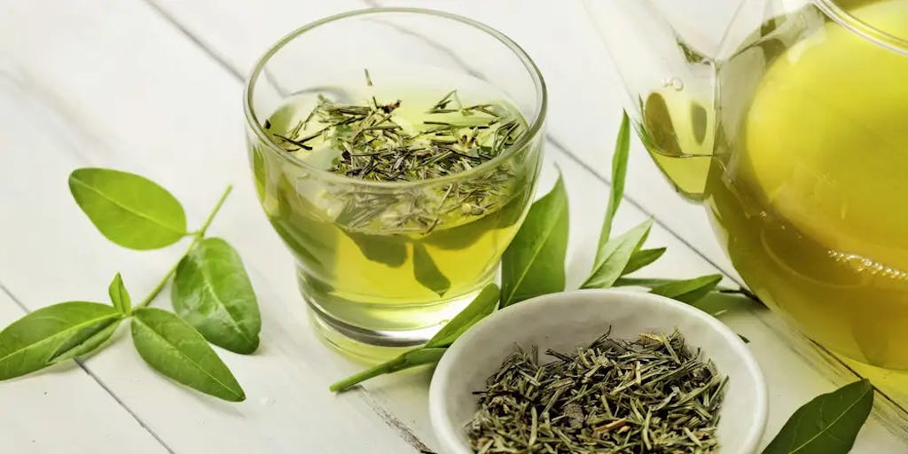 green tea pouring from a kettle into a cup