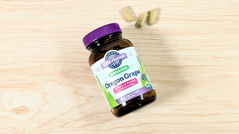 On a wooden surface — a bottle of Oregon’s Wild Harvest Organic Oregon Grape and a three-capsule serving.