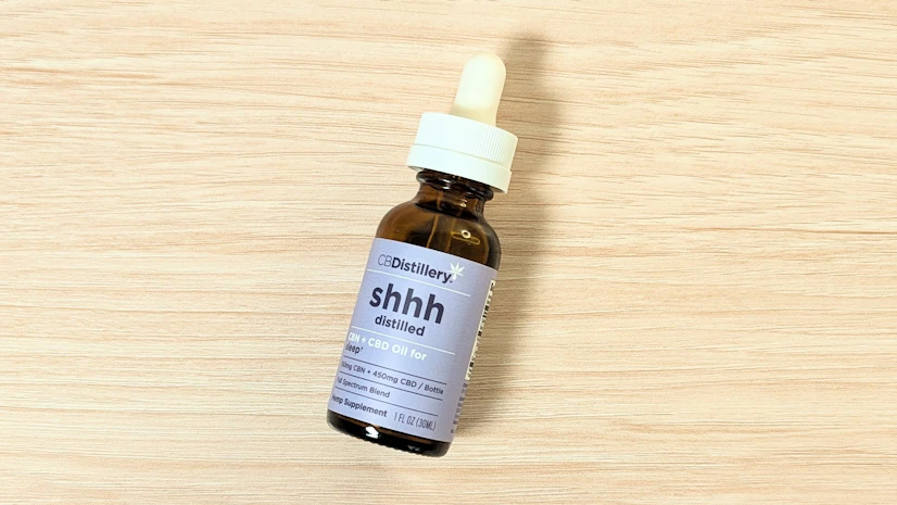 CBDistillery Shhh Distilled CBN + CBD Oil for Sleep, with 300mg CBN and 900mg CBD, on a wood surface