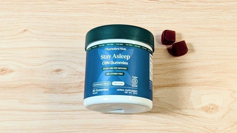 Charlotte’s Web Stay Asleep CBN Gummies on wood surface next to two-gummy serving