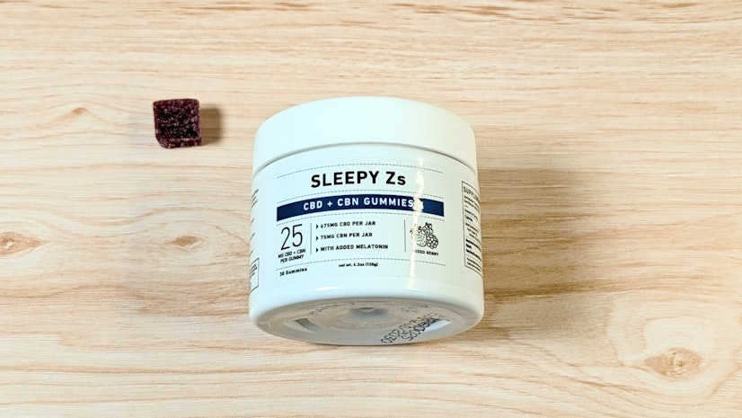 Green Roads Sleepy Zs on wood surface next to one-gummy serving