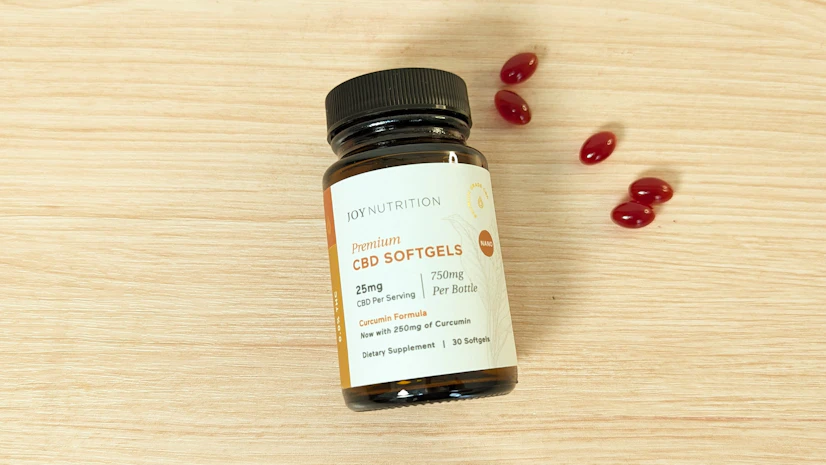 Joy Nutrition THC-Free CBD Softgels With Curcumin on a wood surface