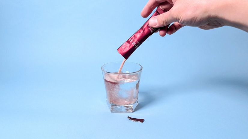 Daily Ultimate Essentials powder poured into a glass of water.