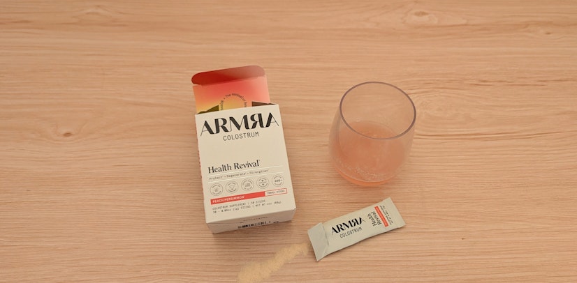 ARMRA colostrum mixed in a glass with packaging next to it