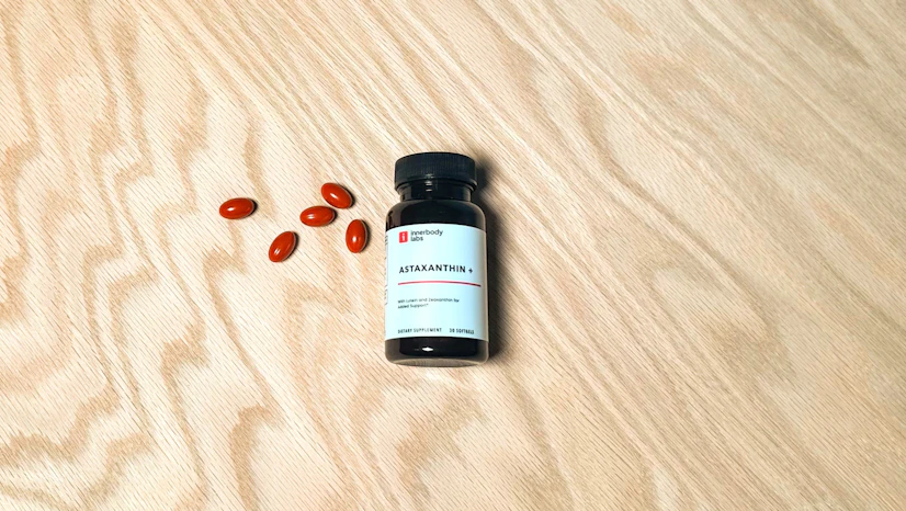 A photo of the Astaxanthin+ supplement bottle taken from the top on a wooden table