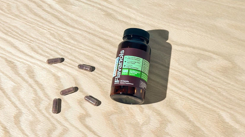 Overhead view of a CocoaVia Cocoa Flavanols bottle on a tabletop with capsules beside it