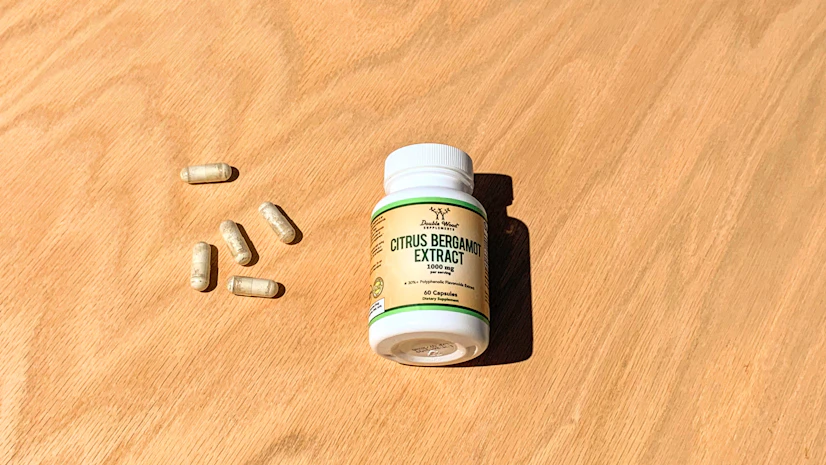 Overhead view of a Double Wood Citrus Bergamot Extract bottle on a tabletop with capsules beside it
