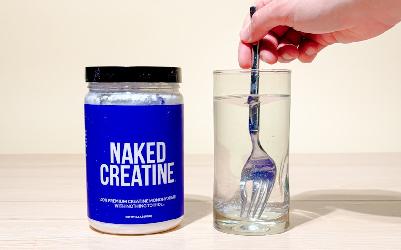 Naked Creatine mixed into a glass on a tan background