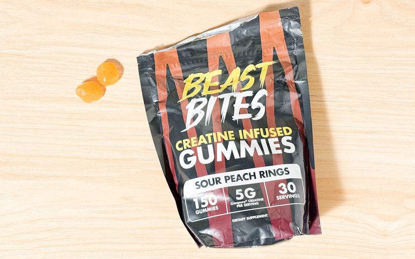 Beast Bites creatine gummies in a pile next to their bag on a wood surface