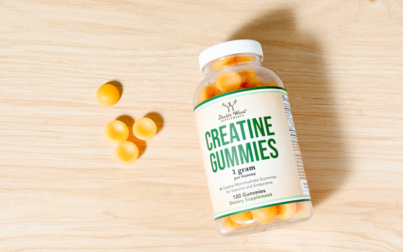 Double Wood creatine gummies in a pile next to their bottle on a wood surface