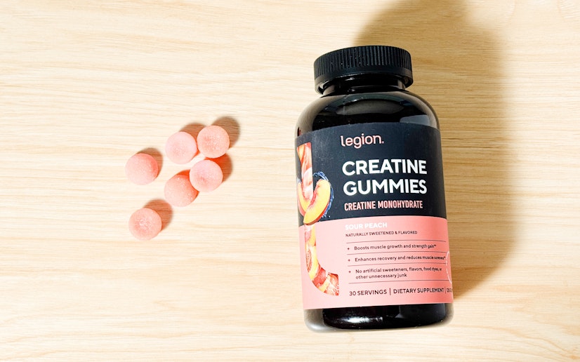 Legion creatine gummies in a pile next to their bottle on a wood surface