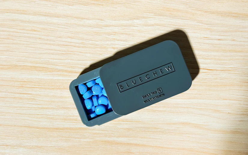 BlueChew tadalafil tablets in their tin on a wood surface
