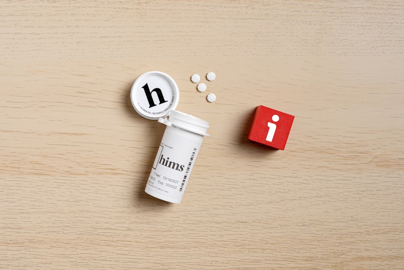 Hims finasteride 1mg prescription tablets for men’s hair loss treatment, with open pill bottle and tablets on wooden surface