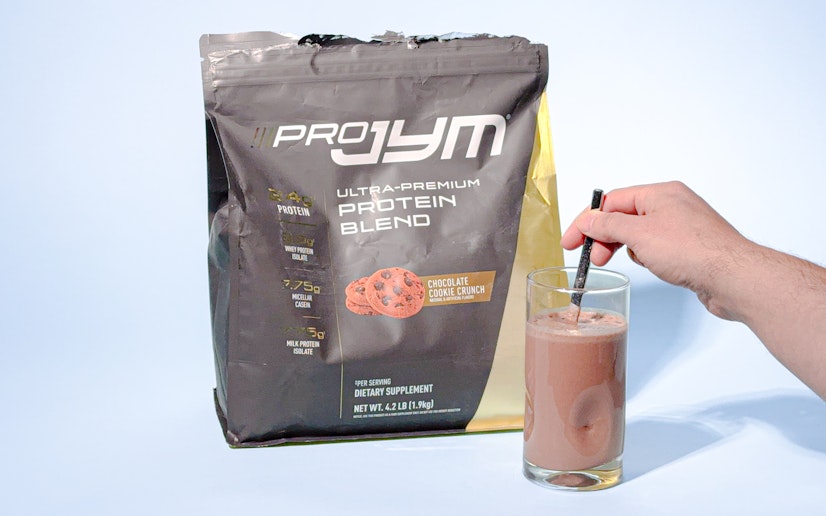 JYM protein in bag and mixed into a glass of water on a blue background.