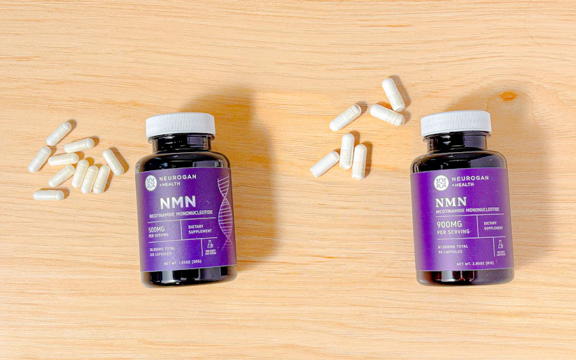 Neurogan NMN 500 and 900 bottles and capsules on a wood surface.