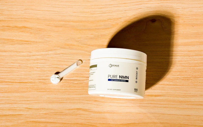 Renue by Science Pure NMN powder and bottle on a wood surface.