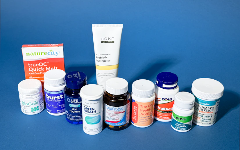 Nearly a dozen different oral probiotic products spread out against a blue background.