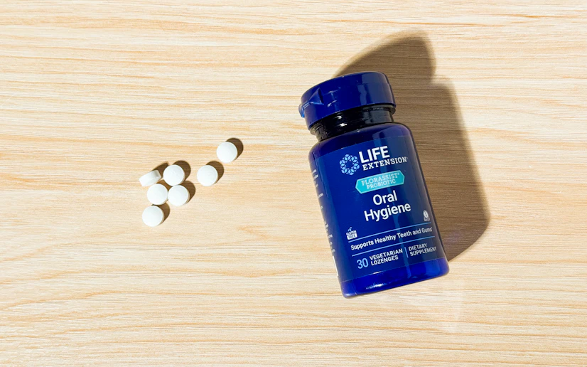 Life Extension FLORASSIST bottle and tablets on a wooden surface.