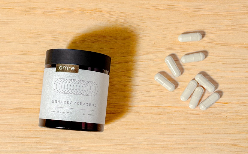 Omre NMN + Resveratrol on a wood surface with capsules poured out