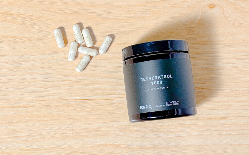 Toniiq Resveratrol 1000 on a wood surface with capsules poured out