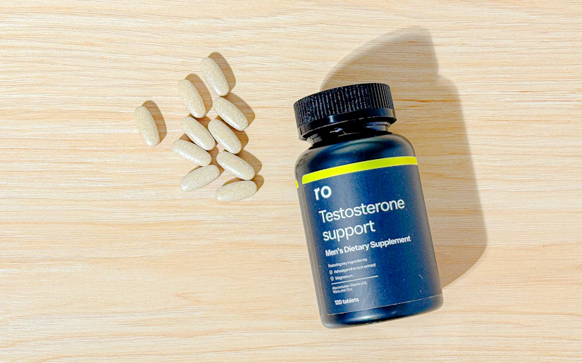 Roman Testosterone Support bottle and tablets on a wood surface.