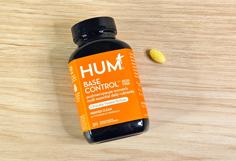 A top-down view of the iron-free HUM Nutrition Base Control bottle on a wood countertop with one tablet