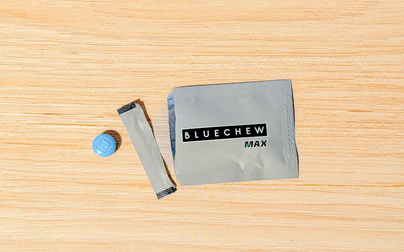 A single BlueChew MAX packet torn open and sitting on a wooden surface next to a chewable tablet.