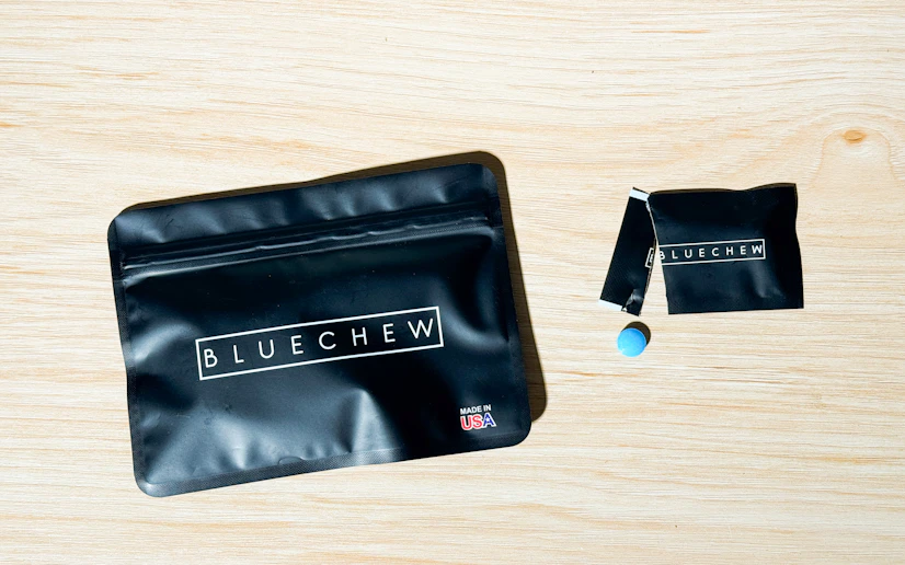 BlueChew sildenafil packaging and tablet on a wood surface.