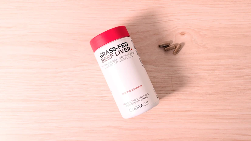 Codeage Grass-Fed Beef Liver, with a three-capsule serving, on a wood surface.