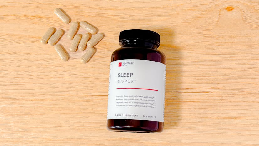 Innerbody Labs Sleep Support supplement bottle and capsules on a wood countertop, from above