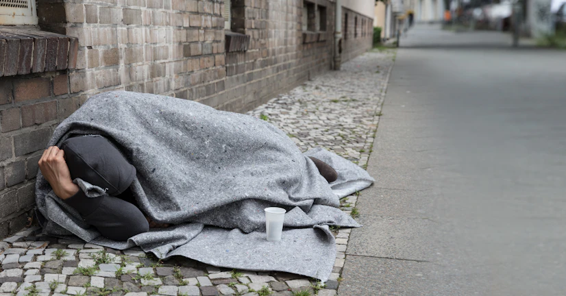 a person without a home sleeping on the sidewalk