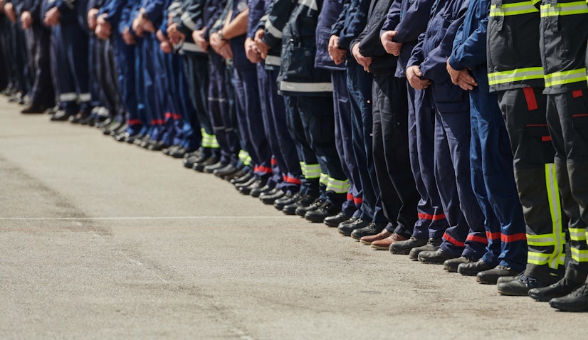 A long row of first responders standing solemnly along a roadside