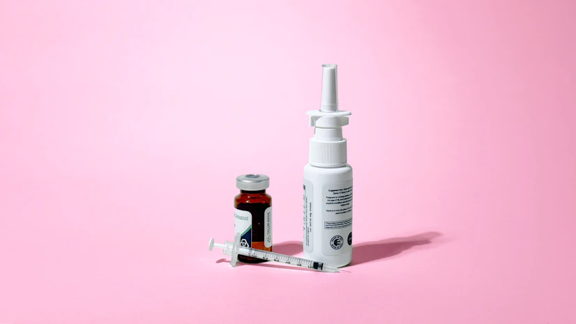 PE-22-28 peptide in a vial with a needle and in a nasal spray bottle against a pink background.