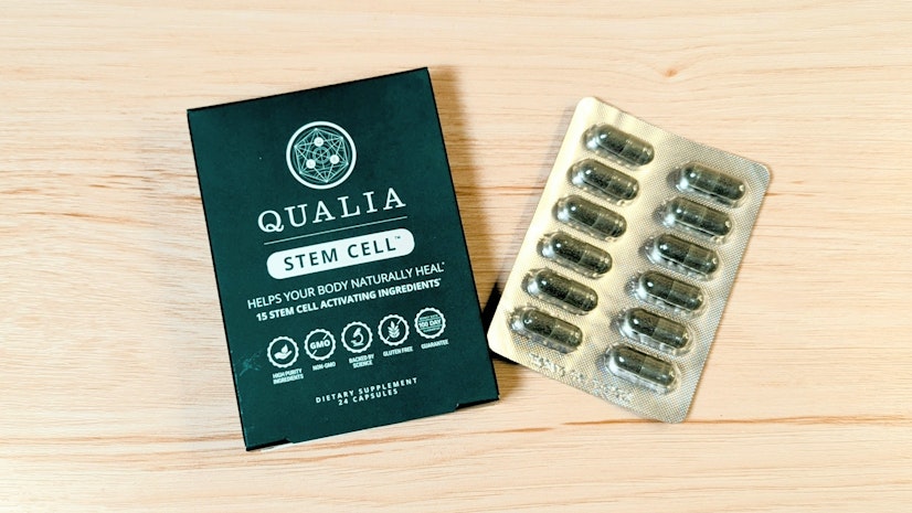 Blister pack of Qualia Stem Cell next to outer packaging, on a wooden surface.